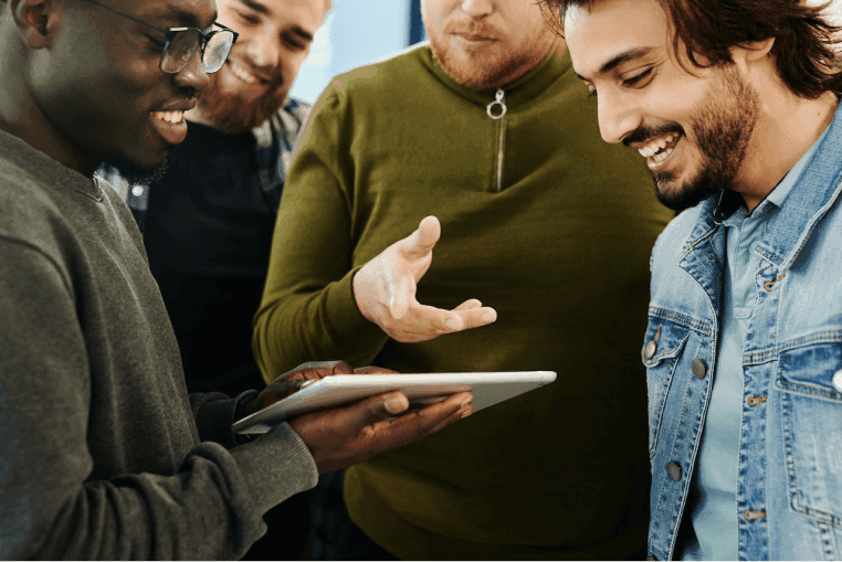 A group of excited co-workers looking at a tablet together