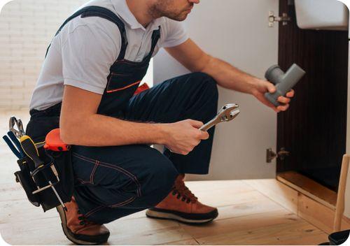 maintenance technician kneeling under a sink