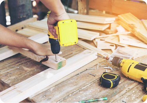 person using drill to screw two pieces of wood together